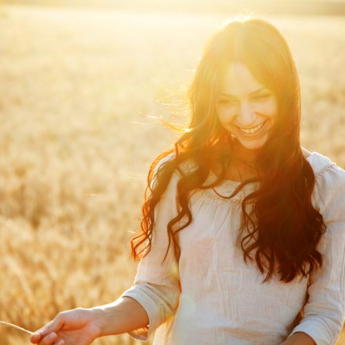 Beautiful brunette lady in wheat field at sunset